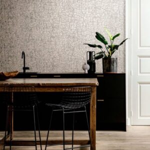 Moderne keuken met Arte Emaille behang, zwart meubilair en houten eettafel met draadstoelen.