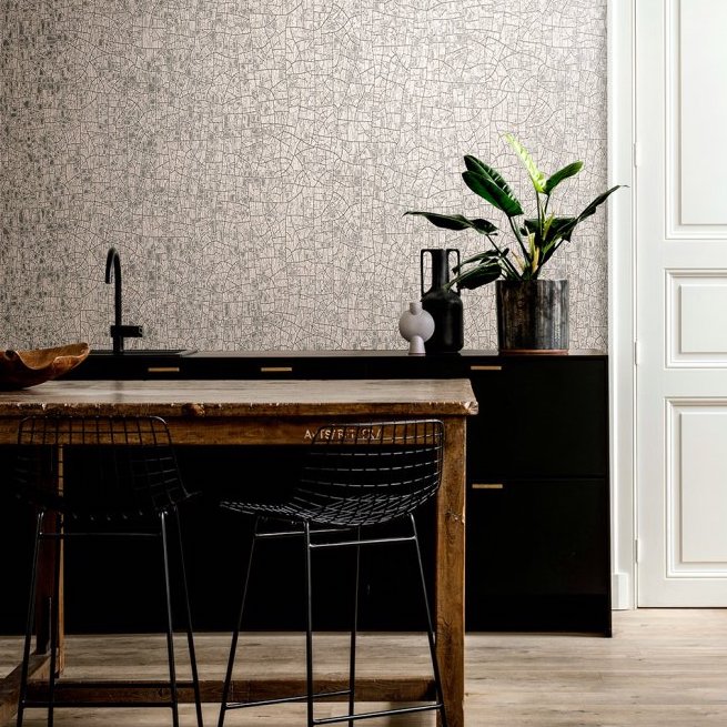 Moderne keuken met Arte Emaille behang, zwart meubilair en houten eettafel met draadstoelen.