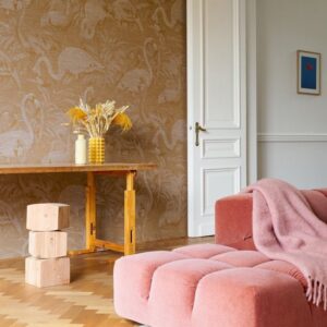 Interieur met Arte-behang "Flamencos Andinos", een roze fluwelen bank en een houten tafel met decoratieve vazen.