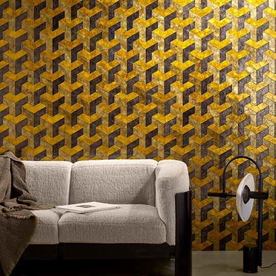 Moderne woonkamer met Arte Helix behang in goud en bruin geometrisch patroon achter een beige bank.