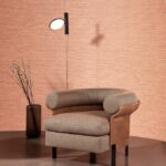 Bruin Arte Koumbala behang met een ronde fauteuil, moderne wandlamp en vaas met takken in een minimalistisch interieur.