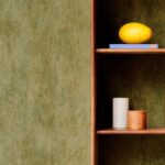 Groen gemêleerd Arte Manchas behang naast een houten plank met decoratieve objecten.
