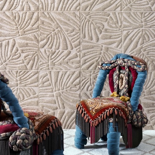 Twee opvallende stoelen met kleurrijke bekleding staan voor een wand met Arte Monstera behang met een reliëf van tropische bladeren.