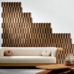 Wand bekleed met geometrisch Arte Prisma behang in bruintinten achter een moderne bank in een stijlvol interieur.