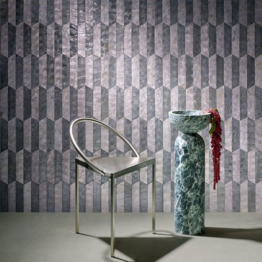 Moderne interieursetting met Arte behang Prisma 33710, een metalen stoel en een marmeren sokkel met schaal en bloemen.