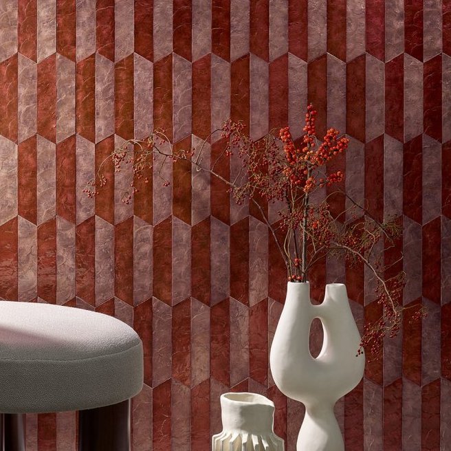 Stijlvolle interieurhoek met Arte behang Prisma 33713 in roodtinten, moderne vazen en een grijze poef.