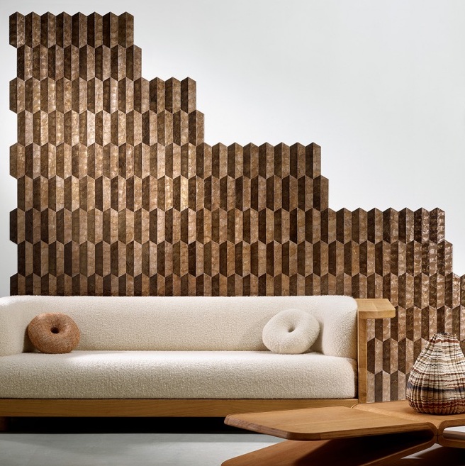 Wand bekleed met geometrisch Arte Prisma behang in bruintinten achter een moderne bank in een stijlvol interieur.