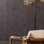 Donker Arte Shibam behang met geometrisch patroon, gecombineerd met een moderne stoel en staande lamp.