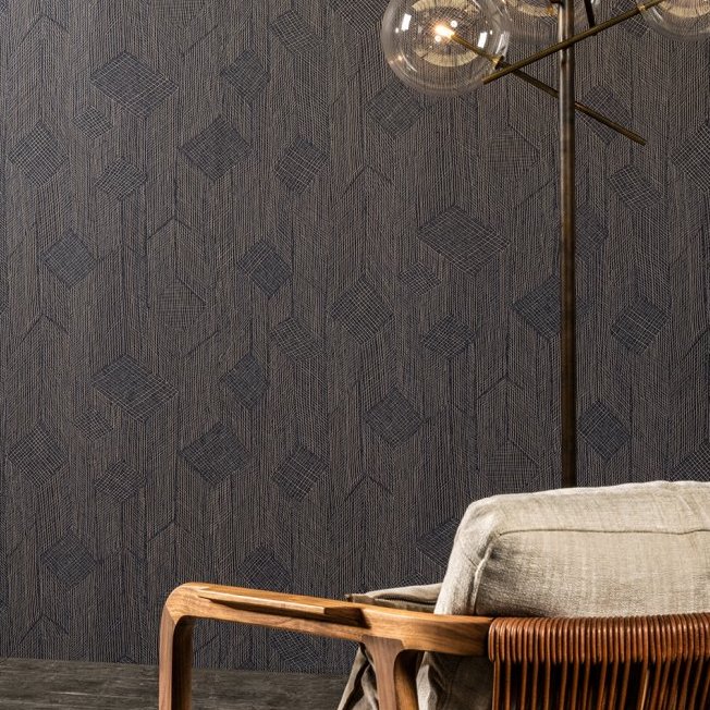 Donker Arte Shibam behang met geometrisch patroon, gecombineerd met een moderne stoel en staande lamp.