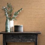 Zwart houten tafeltje met decoratieve objecten voor een muur met Arte behang Timber Copper.