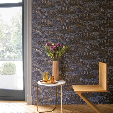 Moderne interieurhoek met CASAMANCE Blossom EDEN behang, een houten designstoel en een ronde tafel met bloemenvaas.