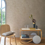 Moderne zithoek met CASAMANCE Alula behang, een houten stoel en een elegante bijzettafel met decoratieve accessoires.