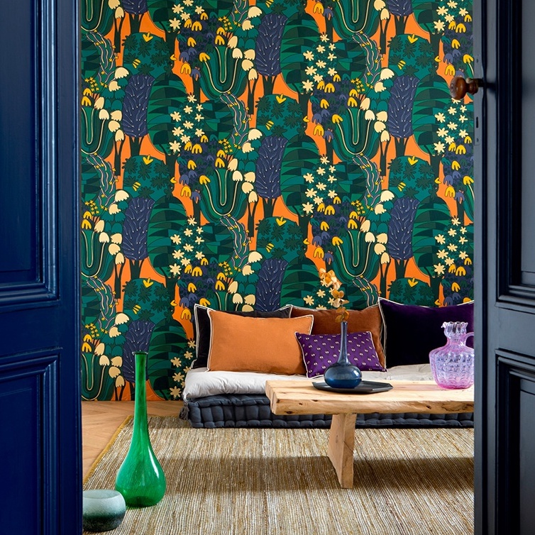 Interieur met kleurrijk Elitis behang Broceliande TP 322 04, lage zitkussens en een houten salontafel.