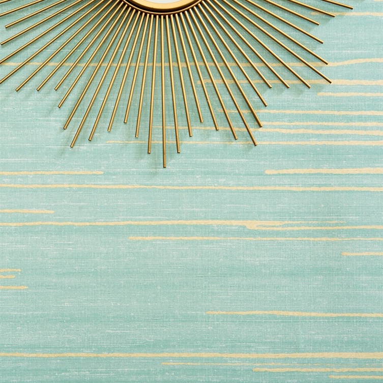 Detail van Elitis behang Kari VP 930 40 met turquoise achtergrond en goudkleurige horizontale accenten, gecombineerd met een decoratieve zonnespiegel.