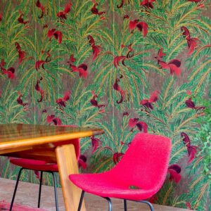 Interieur met Elitis La Californie behang met tropisch motief en felroze stoelen aan een houten tafel.