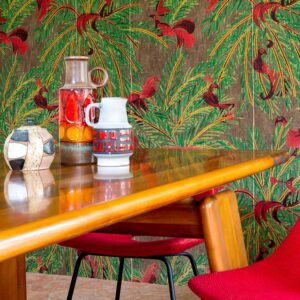 Houten tafel met vintage vazen en kleurrijk Elitis La Californie behang met vogels en palmblaadjes op de achtergrond.