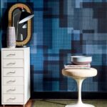 Interieur met Elitis Madras VP 931 80 behang in blauwtonen, een witte ladekast, spiegel met lamp en een designkruk met boeken en een schaal.