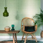Interieur met Elitis behang Nila VP 929 40, een rotan stoel, houten tafel en groene accenten.