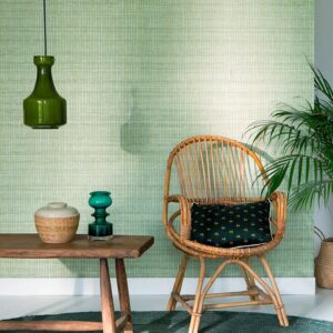 Interieur met Elitis behang Nila VP 929 40, een rotan stoel, houten tafel en groene accenten.