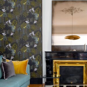 Interieur met Elitis Renard & Co TP 324 05 behang met bosdierenprint, naast een zwarte schouw en grote spiegel.