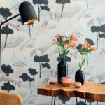 Interieur met Elitis behang Reves de Manille TP 323 01, houten tafel, zwarte vaas met bloemen en moderne zwarte lamp.