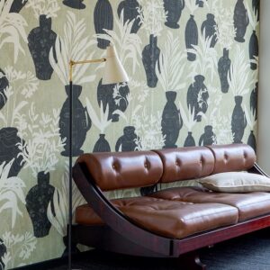 Leren chaise longue voor een wand met Elitis Ulysse VP 925 01 behang met zwarte vazen en plantenmotief.