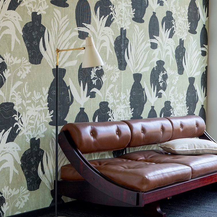 Leren chaise longue voor een wand met Elitis Ulysse VP 925 01 behang met zwarte vazen en plantenmotief.