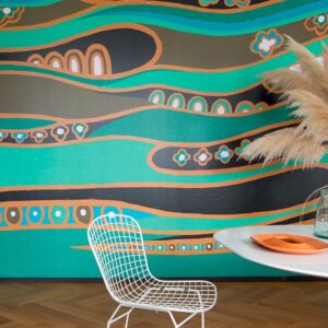 Kleurrijk Elitis Una Storia TP 326 01 behang met golvende patronen in turquoise, oranje en zwart, gecombineerd met een modern interieur.