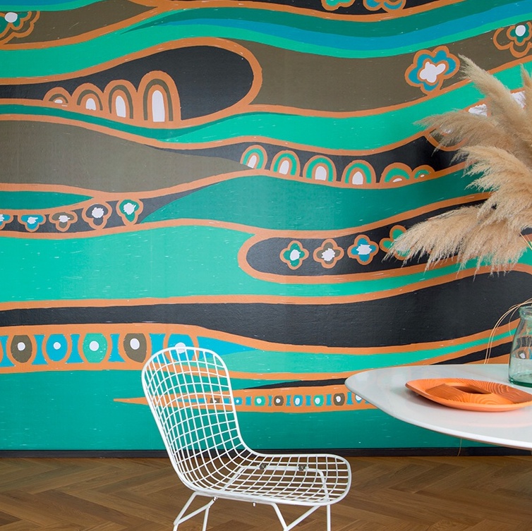 Kleurrijk Elitis Una Storia TP 326 01 behang met golvende patronen in turquoise, oranje en zwart, gecombineerd met een modern interieur.