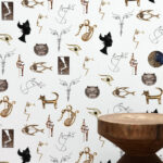 Behang met speelse, artistieke illustraties geïnspireerd op Jean Cocteau, waaronder katten, gezichten, ogen en abstracte figuren.