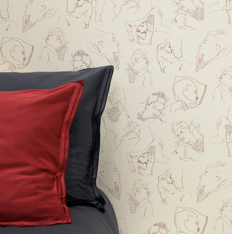 Bed met zwarte en rode kussens staat tegen behang met lijntekeningen van slapende mensen uit de serie "LES DORMEURS".