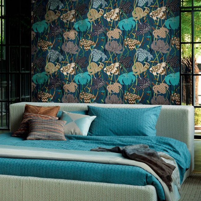 Slaapkamer met een modern bed en opvallend Missoni Lilium 10233-1 behang met kleurrijk bloemenpatroon op de achterwand.