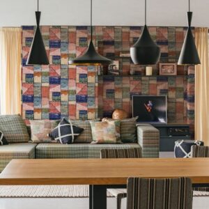Woonkamer met kleurrijk Missoni patchwork-behang, een gestreepte bank en moderne zwarte hanglampen.
