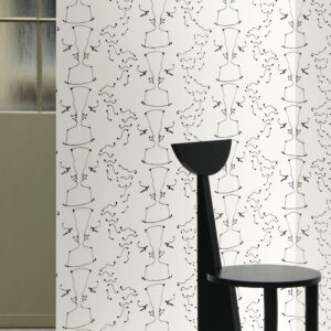 Wit behang met een herhalend abstract lijnpatroon van tegenovergestelde gezichten, genaamd TÊTE À TÊTE, met een zwarte designstoel op de voorgrond.