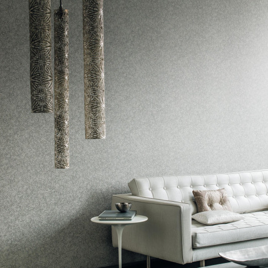 Moderne woonkamer met Dandy Faux Uni Obsessive behang, een lichte bank en stijlvolle hanglampen.