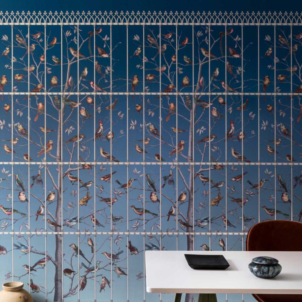 Behang met illustratie van vogels op takken achter een decoratief hek, ontwerp Fornasetti Uccelli.