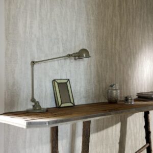 Houten tafel met industriële lamp, fotolijst en accessoires tegen een muur bekleed met Belitung-VP-723-01 behang.