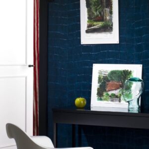Moderne interieurhoek met blauwe Big Croco-structuurwand, een zwarte tafel met kunstobjecten en een witte designstoel.