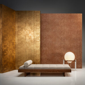 Minimalistisch interieur met een houten daybed, gouden en koperkleurige wandpanelen en een ronde tafellamp.