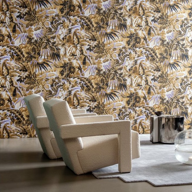 Woonkamer met twee crèmekleurige fauteuils voor een tropisch Buningh Arte Antigua Tropicali behang in bruine en goudtinten.