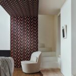 Moderne zithoek met Buningh Arte Chasu behang in rood-zwart patroon op muur en plafond.