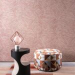 Moderne interieursetting met Buningh Arte Pentagono 33046 behang uit de Antigua collectie, een decoratieve poef met geometrisch patroon en een design bijzettafel met lamp.