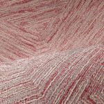 Detailopname van het Buningh-Arte Pentagono 33046 behang uit de Antigua collectie met een reliëfstructuur en rood-beige geweven patroon.