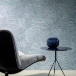 Modern interieur met Buningh-Arte Pentagono 33048 behang uit de Antigua collectie, een loungestoel en een blauw bijzettafeltje met decoratieve vaas.