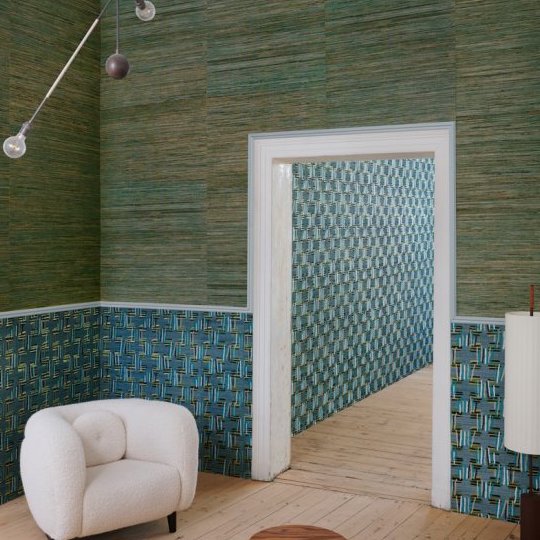 Interieur met Buningh Arte Sambe 54551 behang in groene en blauwe tinten, met een witte fauteuil en houten vloer.