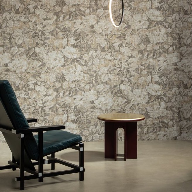 Stijlvolle woonkamer met Buningh Arte Stagionato 33012 bloemenbehang uit de Antigua collectie, een moderne stoel, een bijzettafel en een ronde hanglamp.