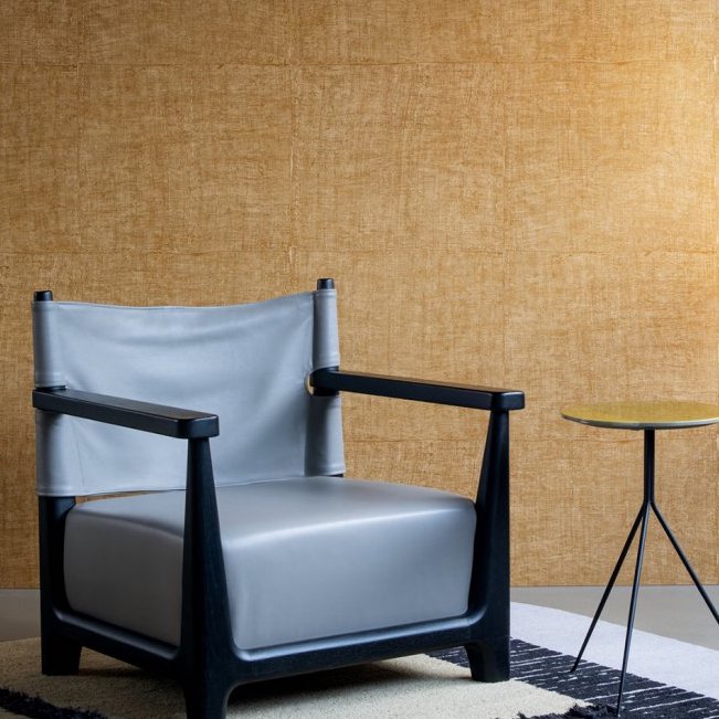 Grijze designstoel en bijzettafel voor een muur met Buningh Arte Tintura 33023 behang uit de Amaranth Antigua collectie.