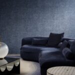 Donkerblauwe woonkamer met een fluwelen bank en Buningh Arte Tintura 33026 behang uit de Amaranth Antigua collectie.
