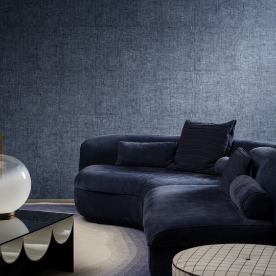 Donkerblauwe woonkamer met een fluwelen bank en Buningh Arte Tintura 33026 behang uit de Amaranth Antigua collectie.