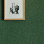 Ingelijste abstracte kunst aan een groene textiele wand uit de Lin Brodés collectie van Elitis.